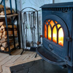 Cast,Iron,Stove,With,Fire,And,Stacked,Wood,Beside