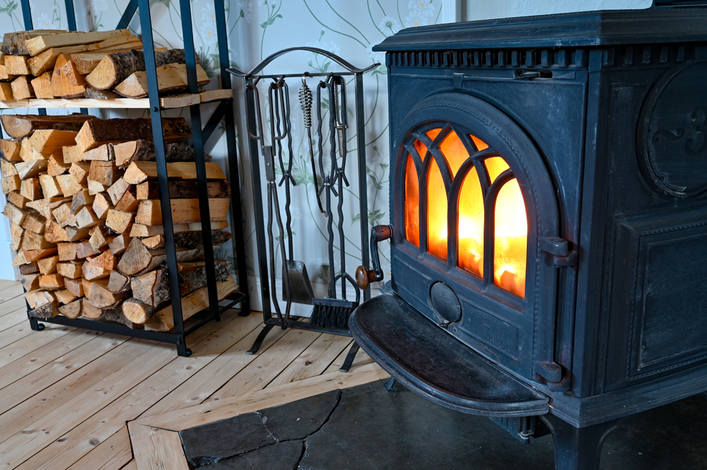 Cast,Iron,Stove,With,Fire,And,Stacked,Wood,Beside