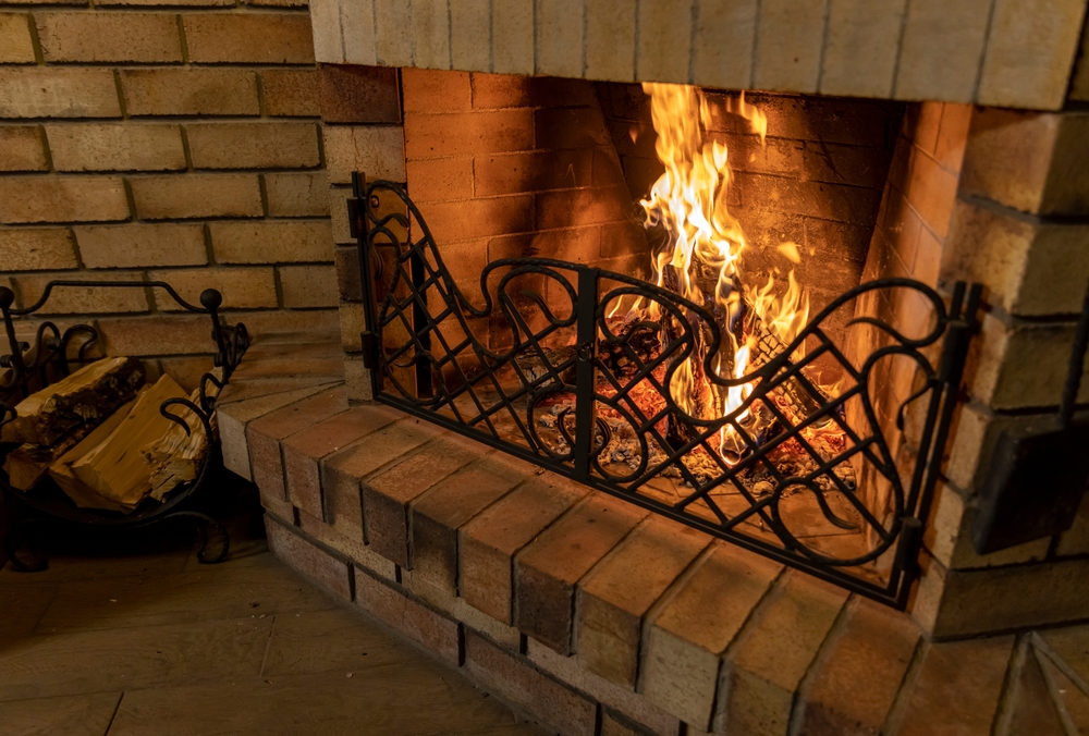 Old,Brick,Fireplace,With,A,Forged,Grate,And,Burning,Wood